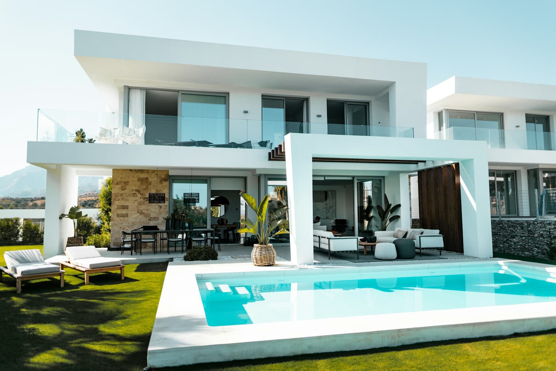 Open living volumes around a rectangular pool, hills beyond.